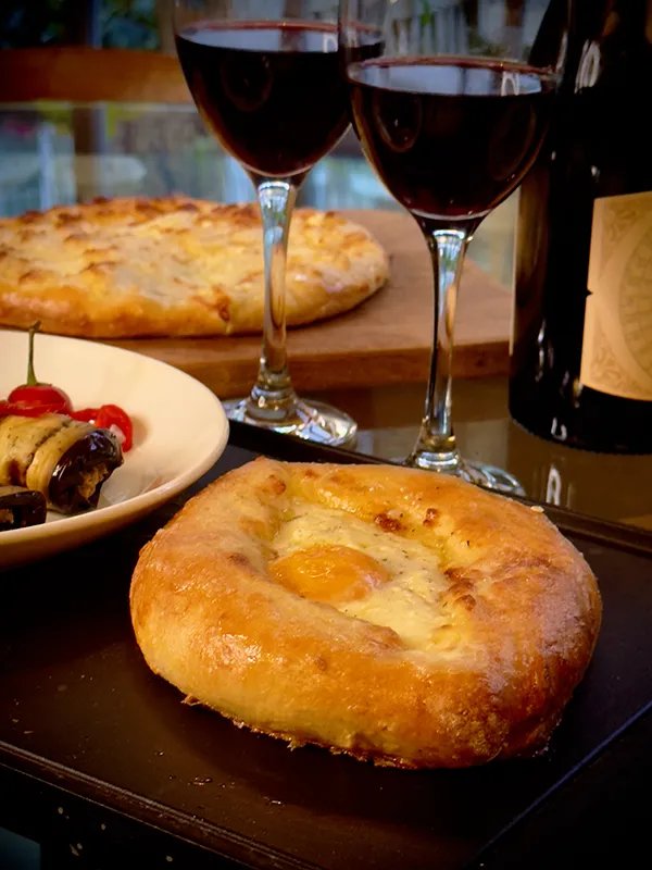 2 khachapuris and wine on a dinner table